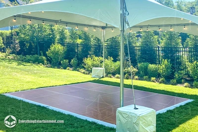 Cherry wood dance floor set up under high peak tent on grass in Westfield, NJ