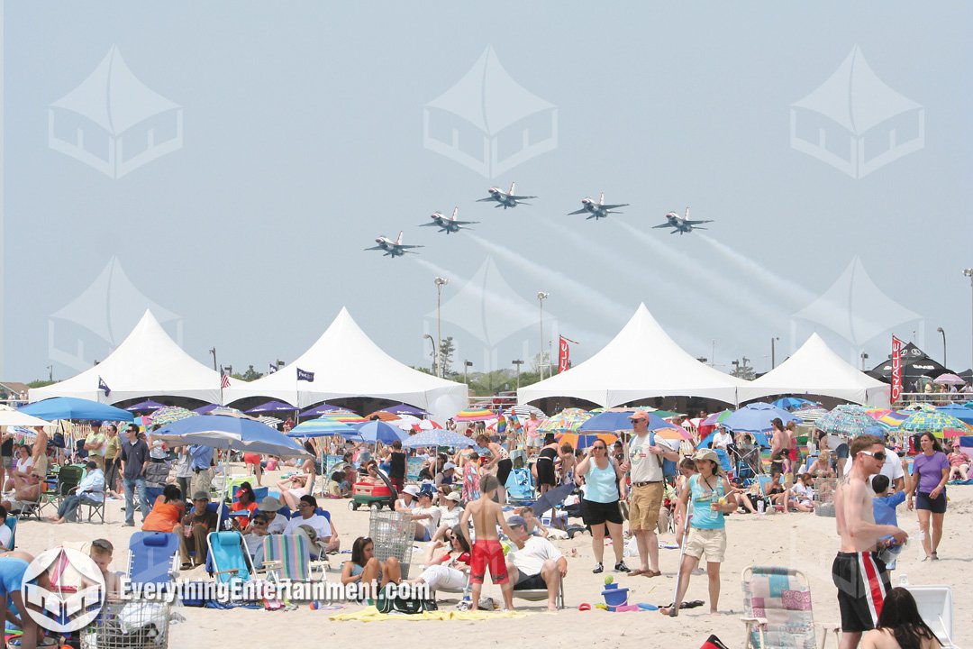 High peak VIP chalet tents set up on the beach for the New York Air Show at Jones Beach with jet formations overhead by Everything Entertainment.