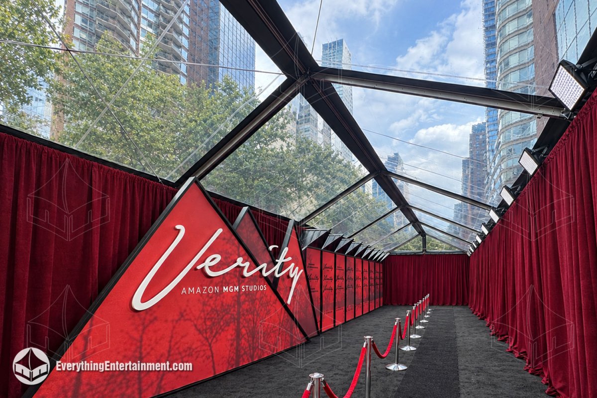 Interior view of a 20x75 clear top premiere tent with red drapes, subflooring, and stanchions by Everything Entertainment