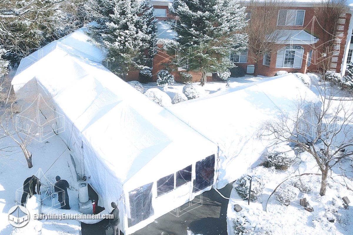 Aerial view of a custom angled maxi-frame tent setup over a snow-covered curved driveway, featuring propane heaters and sidewalls installed by Everything Entertainment.