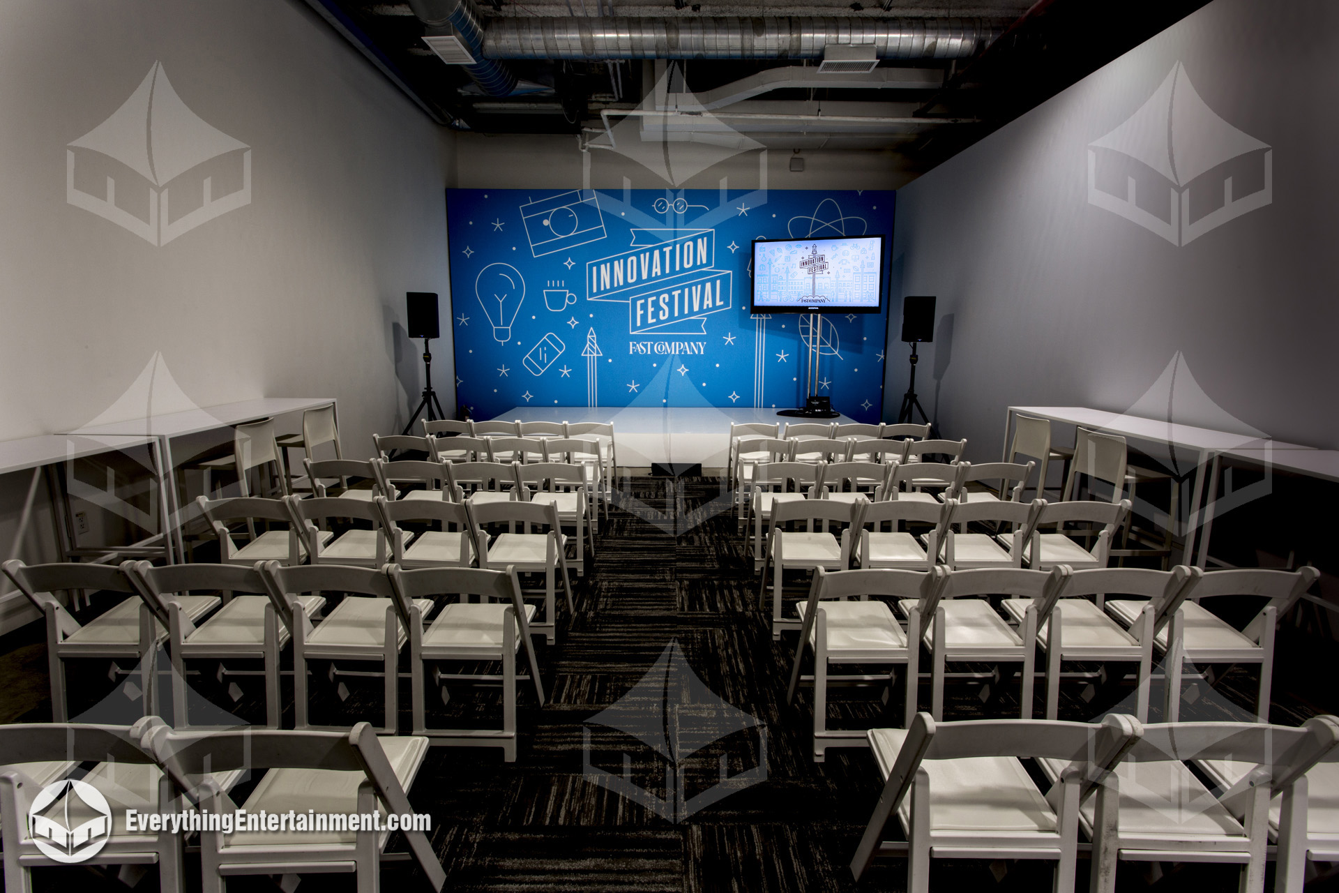 A sleek stage setup with a branded backdrop, premium seating, and video displays, perfect for high-impact presentations.