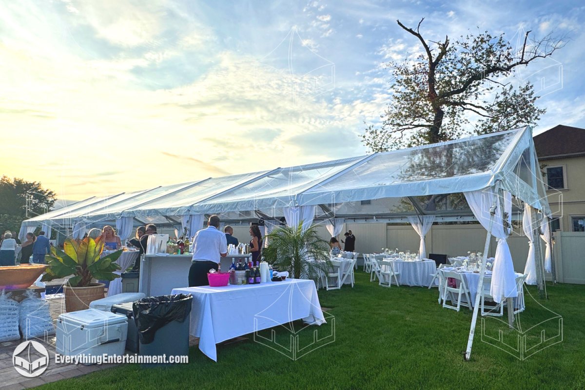 Sunlit interior of a clear top wedding tent with a cherry dance floor, tables, and chairs on Staten Island by Everything Entertainment