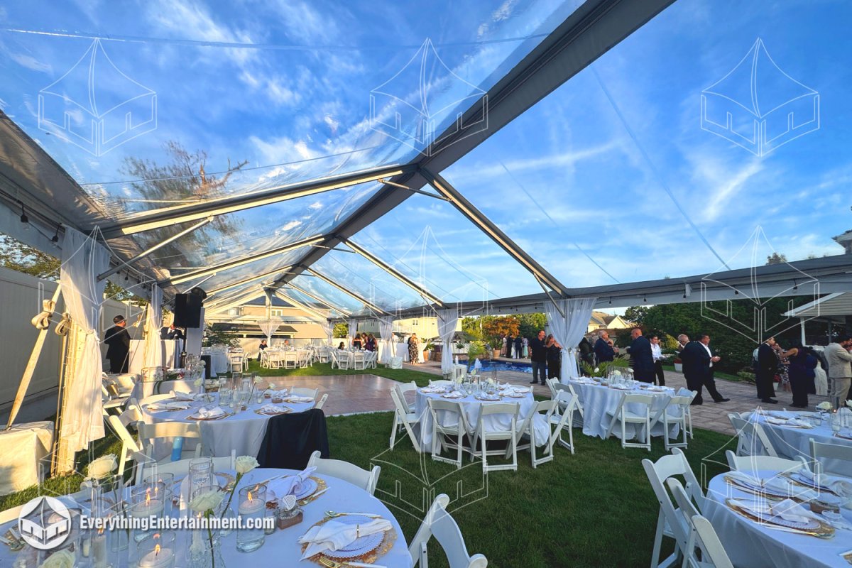 Exterior of a 25x90 clear top frame tent with white leg drapes in a Staten Island backyard by Everything Entertainment.