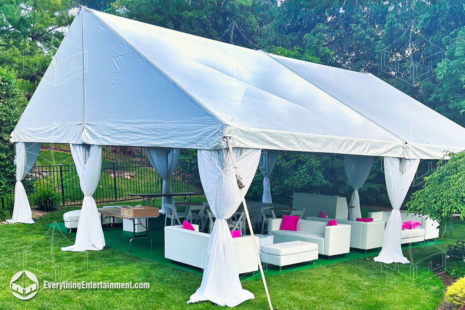 Elegant white fabric concealing aluminum tent legs in a backyard tent setup with lounge furniture